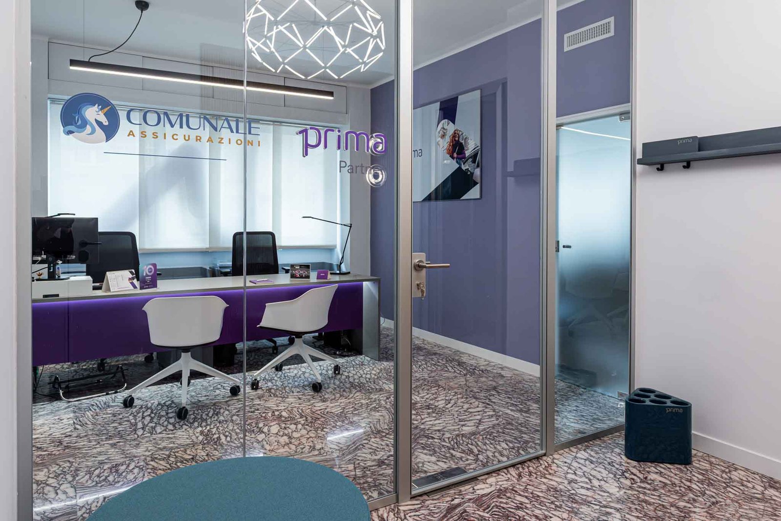 Angolo ufficio Comunale Srl Bari con secondo ambiente di consulenza e vetrina Prima Partner, design moderno con tonalità viola e sedute bianche